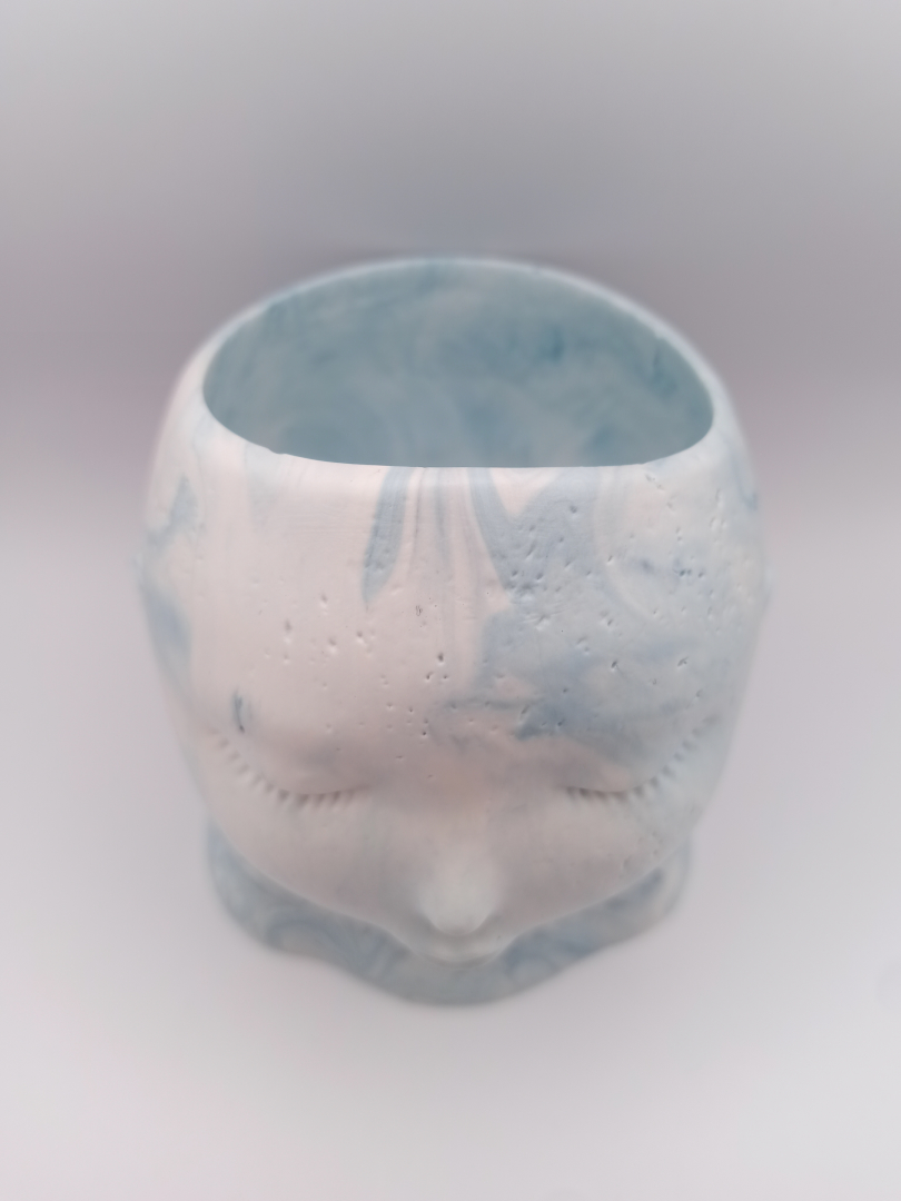 vue du dessus d'un pot en forme de visage aux traits fins et délicats fabriqué en Jesmonite couleur bleu clair oslo marbré