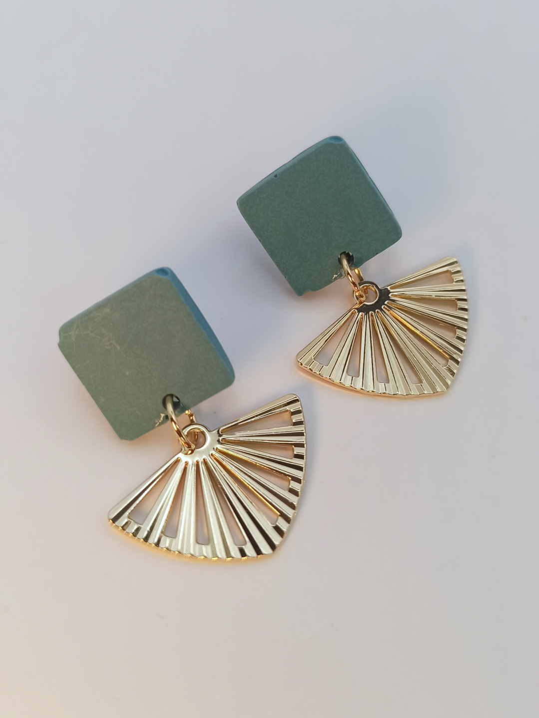 boucles d'oreilles courtes puces carrés en Jesmonite de couleur bleu gris avec un pendentif éventail ajouré en acier inoxydable doré