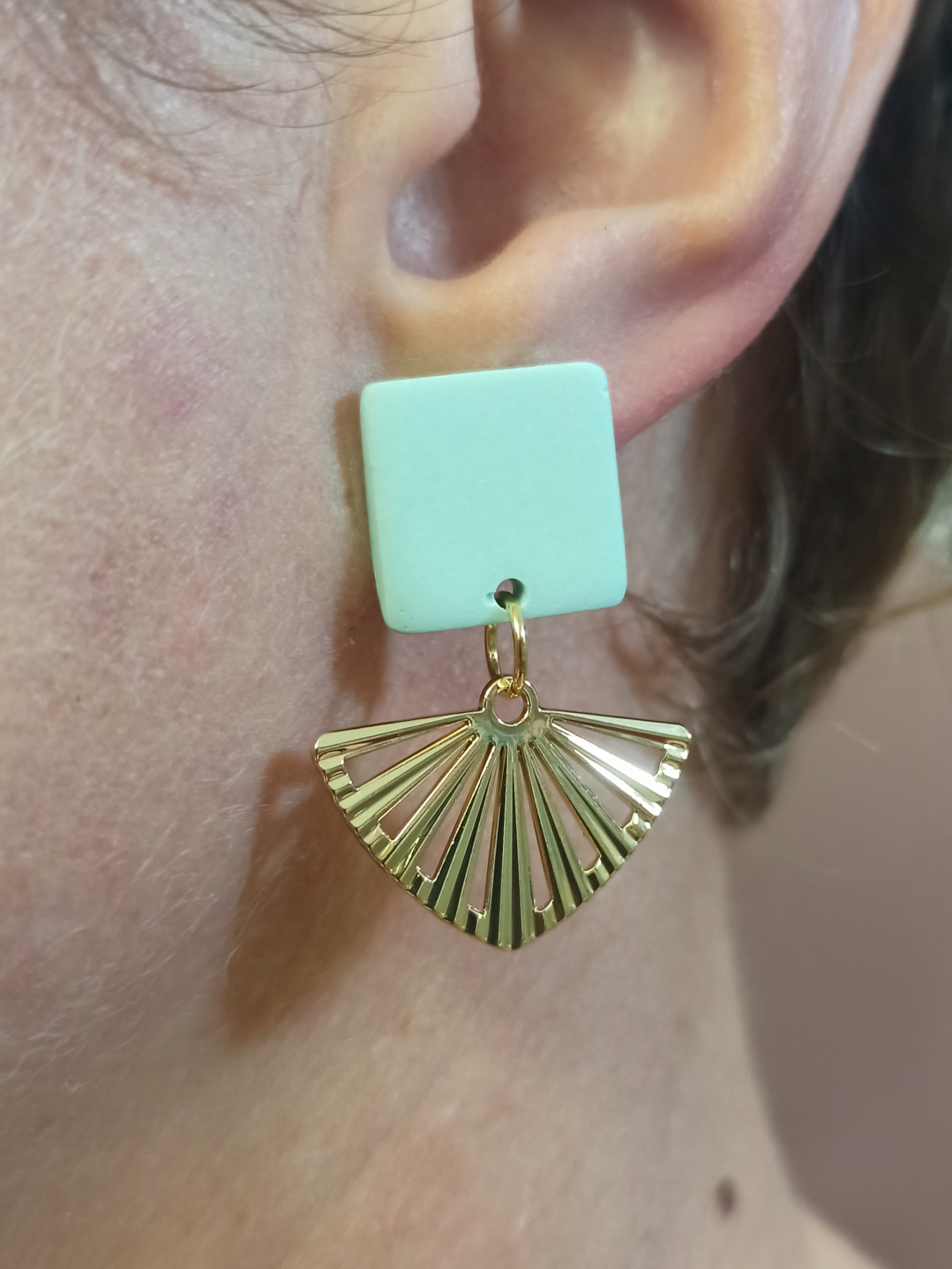 mise en situation portées de boucles d'oreilles courtes puces carrés en Jesmonite de couleur mint avec un pendentif éventail ajouré en acier inoxydable doré