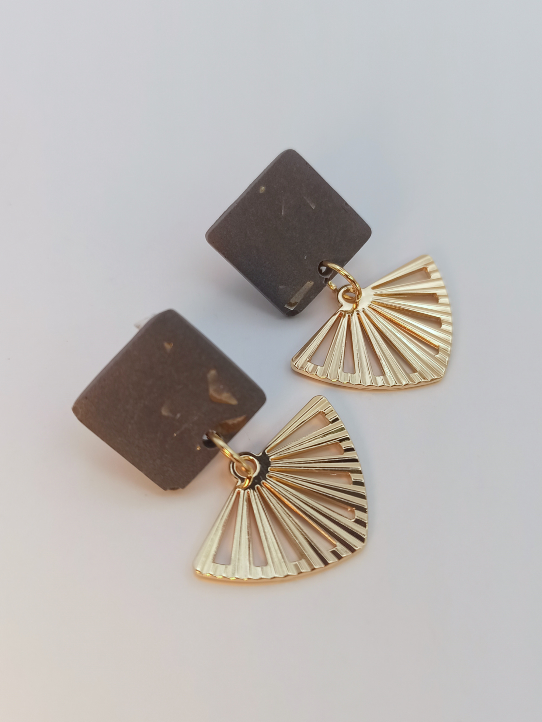 boucles d'oreilles courtes puces carrés en Jesmonite de couleur gris foncé paillettes dorées avec un pendentif éventail ajouré en acier inoxydable doré