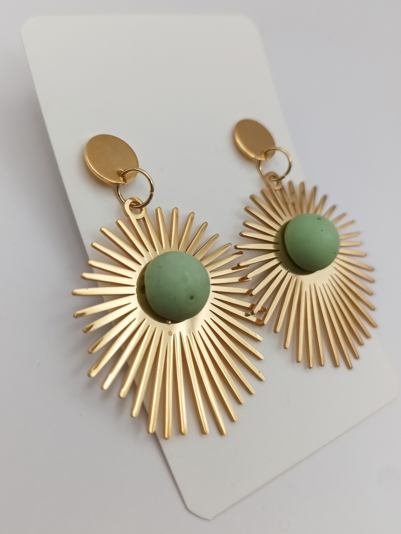 boucles d'oreilles en forme de grands soleils en acier inoxydable doré avec une pièce en Jesmonite de couleur vert sauge en son centre attaches puces en acier inoxydable doré lisse