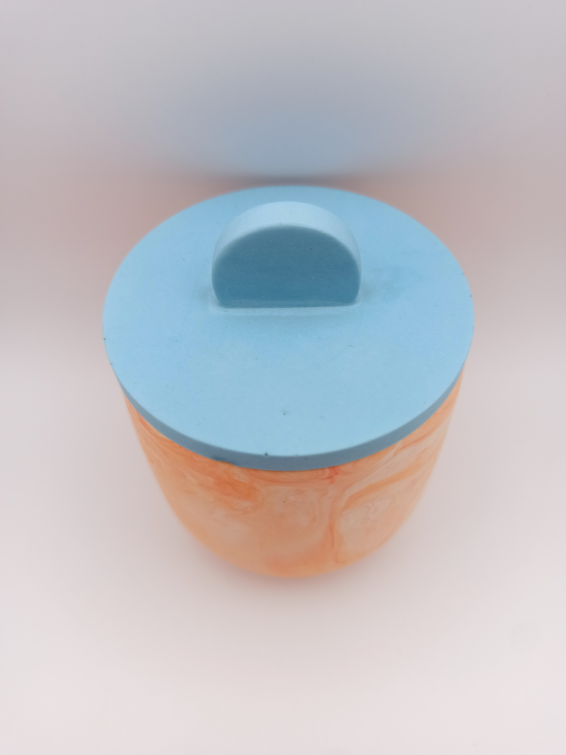vue du dessus d'un petit pot en Jesmonite orange marbré et couvercle bleu clair design épuré lisse